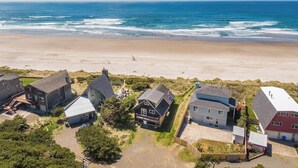An aerial view of a coastal residential area with houses near the beach, a clear sky, and the ocean in the background. - The Lookout - Beachfront, amazing views, spacious home (Cloverdale)
