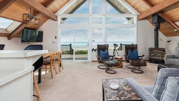 A spacious loft with a high ceiling, large windows, a cozy seating area, and a fireplace. - The Lookout - Beachfront, amazing views, spacious home (Cloverdale)