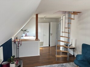 Een modern interieur met een houten trap, een blauwe stoel en een keukenhoek.