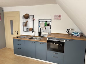 A compact kitchen with a sink, stove, and storage cabinets.