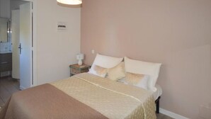 A bedroom with a bed, a nightstand, a lamp, and a door leading to a bathroom. - Villa with terrace 300 m from the sea (Antibes)