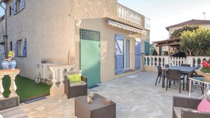 An outdoor patio area with stone flooring, wicker furniture, and a small garden. - Villa with terrace 300 m from the sea (Antibes)