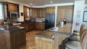 A spacious kitchen with dark wood cabinets, granite countertops, stainless steel appliances, and a central island with seating.