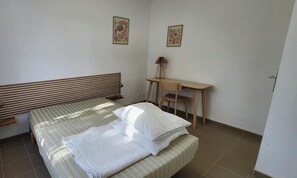 Un dormitorio con una cama, un escritorio y dos cuadros en la pared.