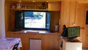 A compact kitchen with a window, a refrigerator, a sink, and a small table with a floral tablecloth.
