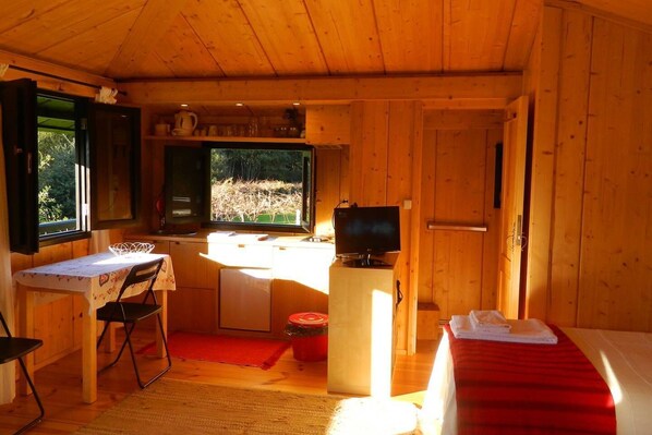 A compact cabin with a kitchenette, a dining area, and a sleeping area.