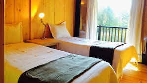 A room with two beds, wooden walls, a nightstand with a lamp, and a balcony with a railing. - Treehouse Quinta Lamosa (Arcos de Valdevez)