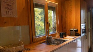 A kitchen with wooden cabinets, a large window, and a sign that reads "TEA LIFE". - Treehouse Quinta Lamosa (Arcos de Valdevez)