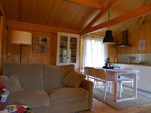Un intérieur en bois comprenant un canapé, une table à manger, des chaises et un coin cuisine.