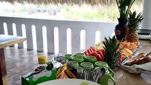 A buffet setup with various food items and a thatched roof structure. - Private room with king size bed num023 (Brisas de Zicatela)
