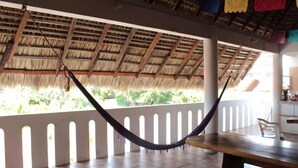 A room with a thatched roof, a hammock, and a view of greenery outside. - Private room with king size bed num023 (Brisas de Zicatela)