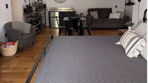 Un espacio habitable compacto con cama, zona de comedor, kitchenette y sofá.