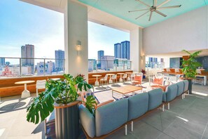 A rooftop lounge with seating, tables, and a city view.