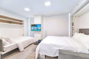 Une chambre d’hôtel moderne dotée de deux lits, d’un téléviseur à écran plat, d’étagères intégrées et offrant une vue sur la ville.