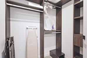 Ein modernes Badezimmer mit integrierter Waschmaschine, einem Wäscheständer und einem Regal mit einem blauen Bügeleisen.