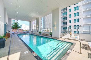 Piscina interior moderna com água cristalina, rodeada por espreguiçadeiras e plantas em vasos.