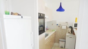 Een kleine keuken met een koelkast, oven, magnetron en spoelbak.