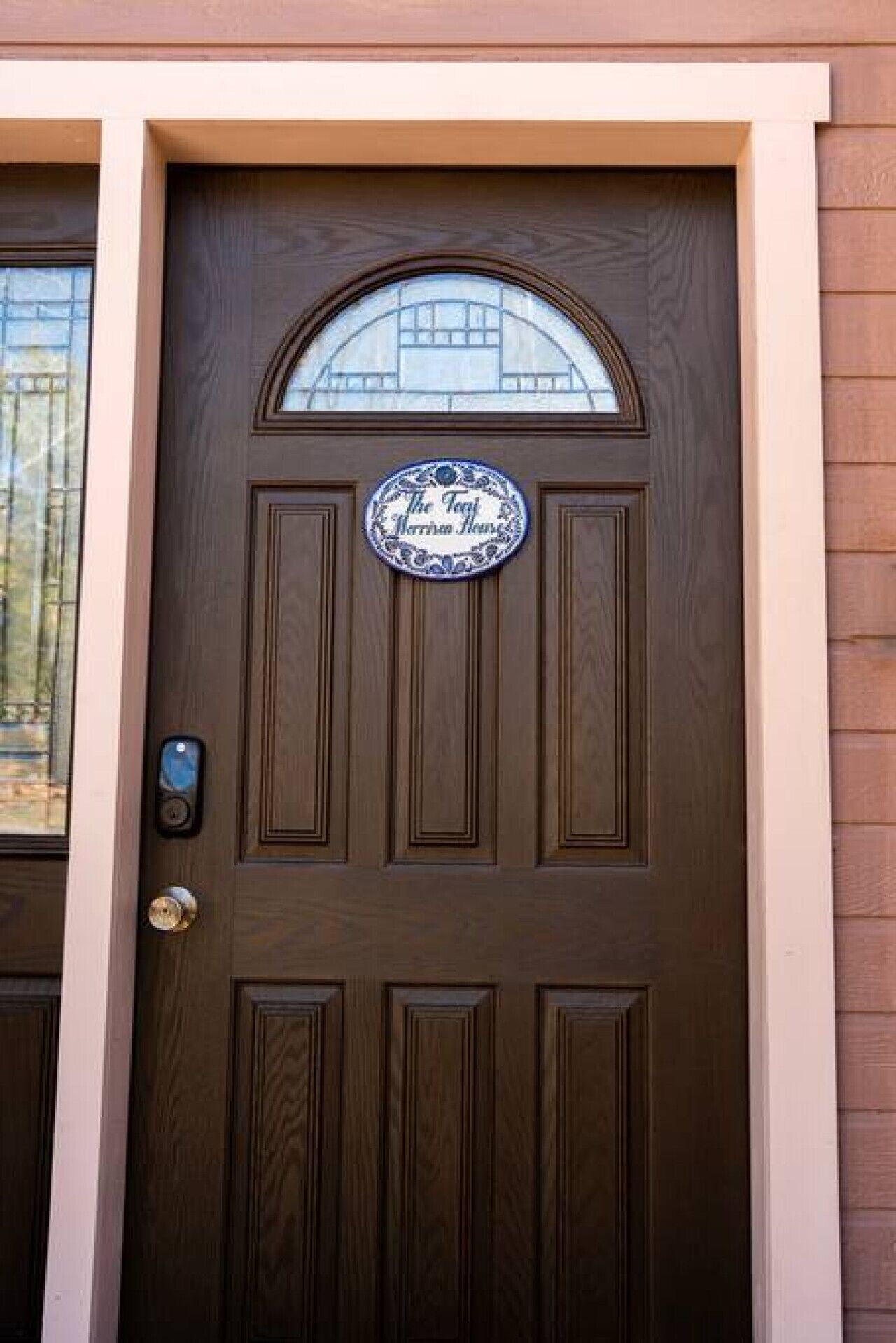 A brown wooden door with a glass window above it and a circular sign with text.
