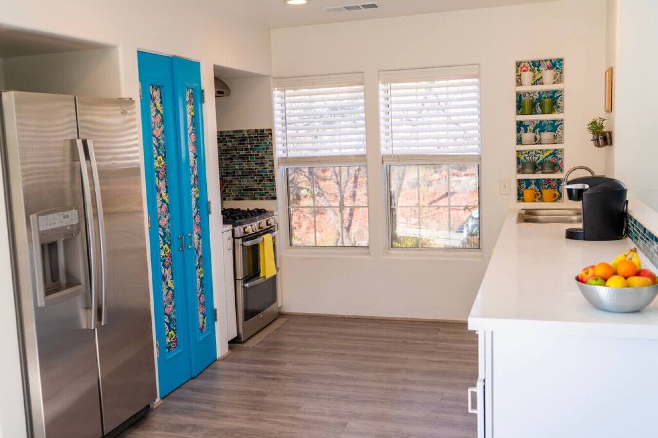 Una cocina moderna con un refrigerador de acero inoxidable, una estufa a gas y una encimera blanca.