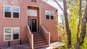 A two-story building with a front entrance, a staircase, and a small porch area. - Charming & Artsy Half-House, Walk to Best of Sedona! Views, Yard & Firepit (Sedona)