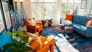 A modern living room with a blue sofa, orange armchairs, and a patterned rug. - Charming & Artsy Half-House, Walk to Best of Sedona! Views, Yard & Firepit (Sedona)