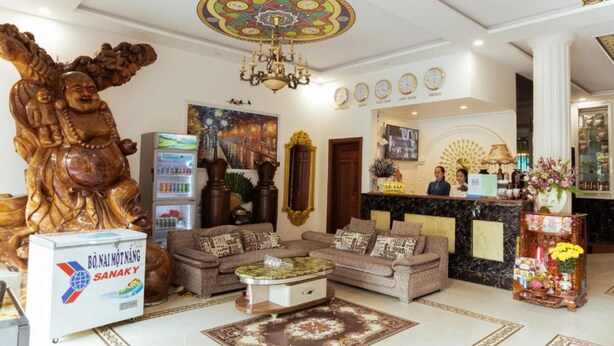 A hotel lobby with a reception desk, sofas, a chandelier, and a large Buddha statue. - Window 1 Hotel (Kon Tum)