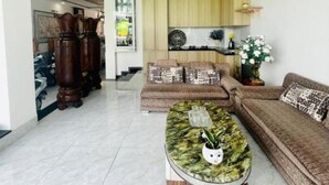 A modern living room with a marble coffee table, a sofa, and a kitchen area in the background. - Window 1 Hotel (Kon Tum)