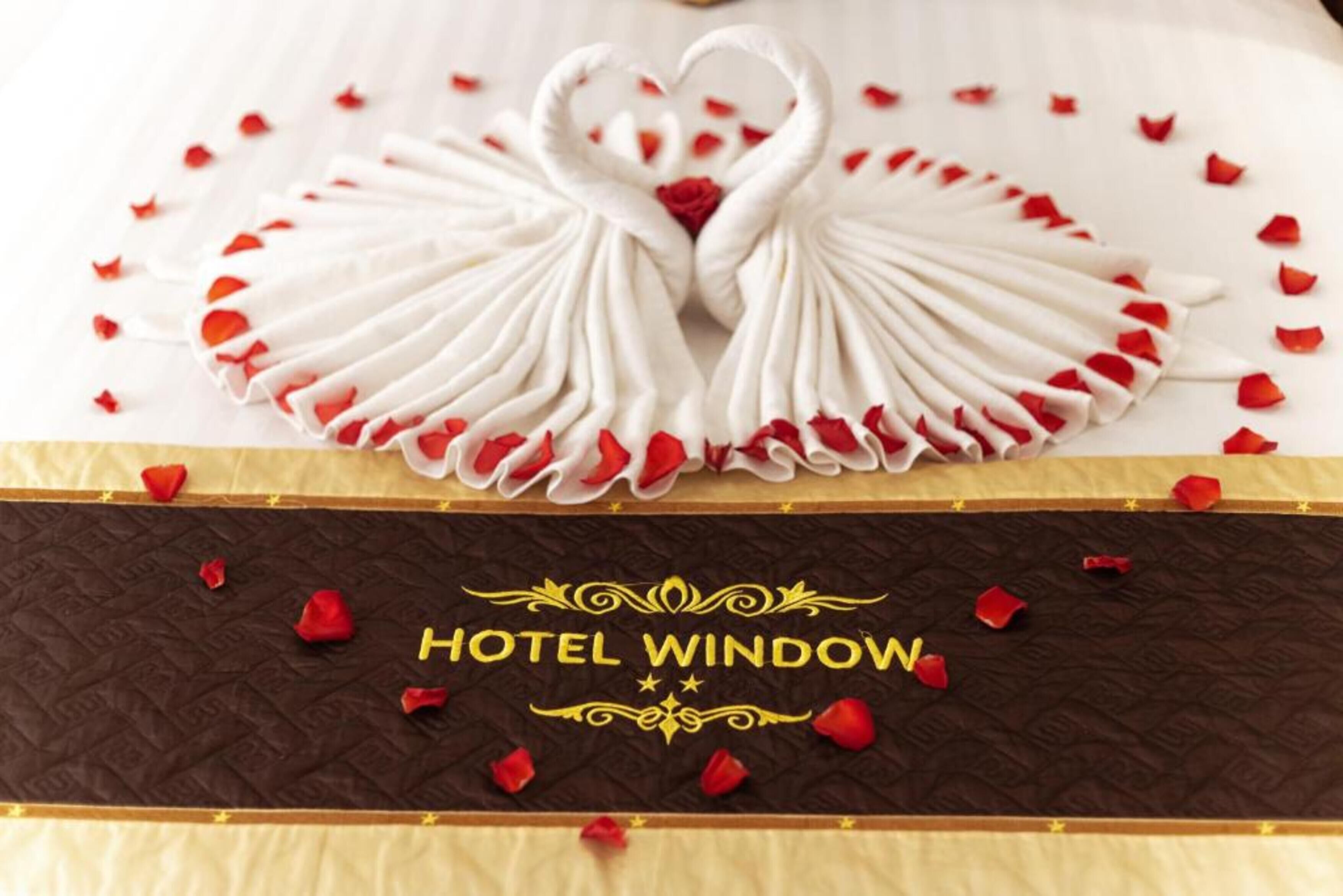 Una cama con diseño floral blanco y rojo, un cabecero color chocolate y el texto "HOTEL WINDOW".