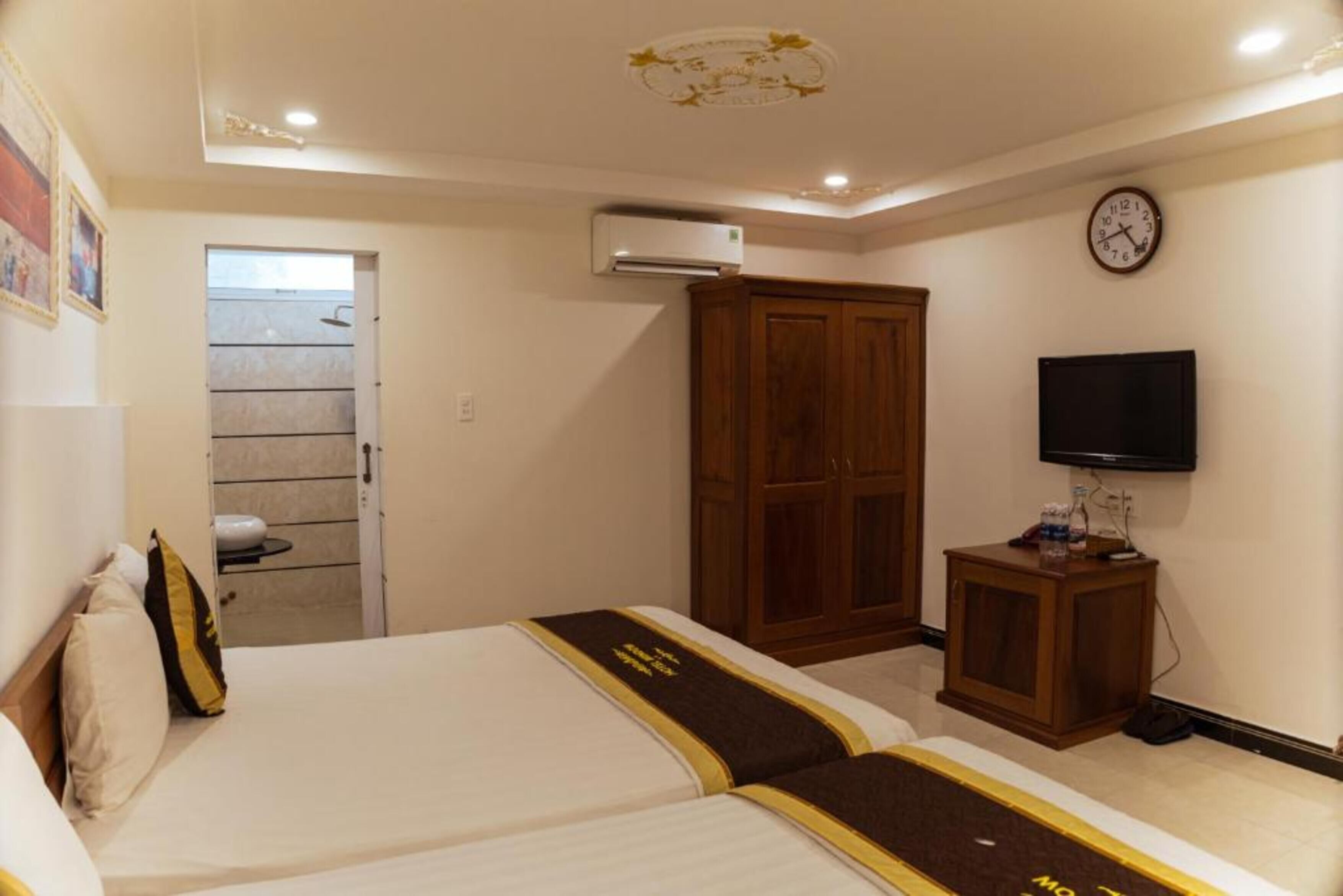 Ein Hotelzimmer mit zwei Betten, einem Fernseher, einem Kleiderschrank und einer Klimaanlage.