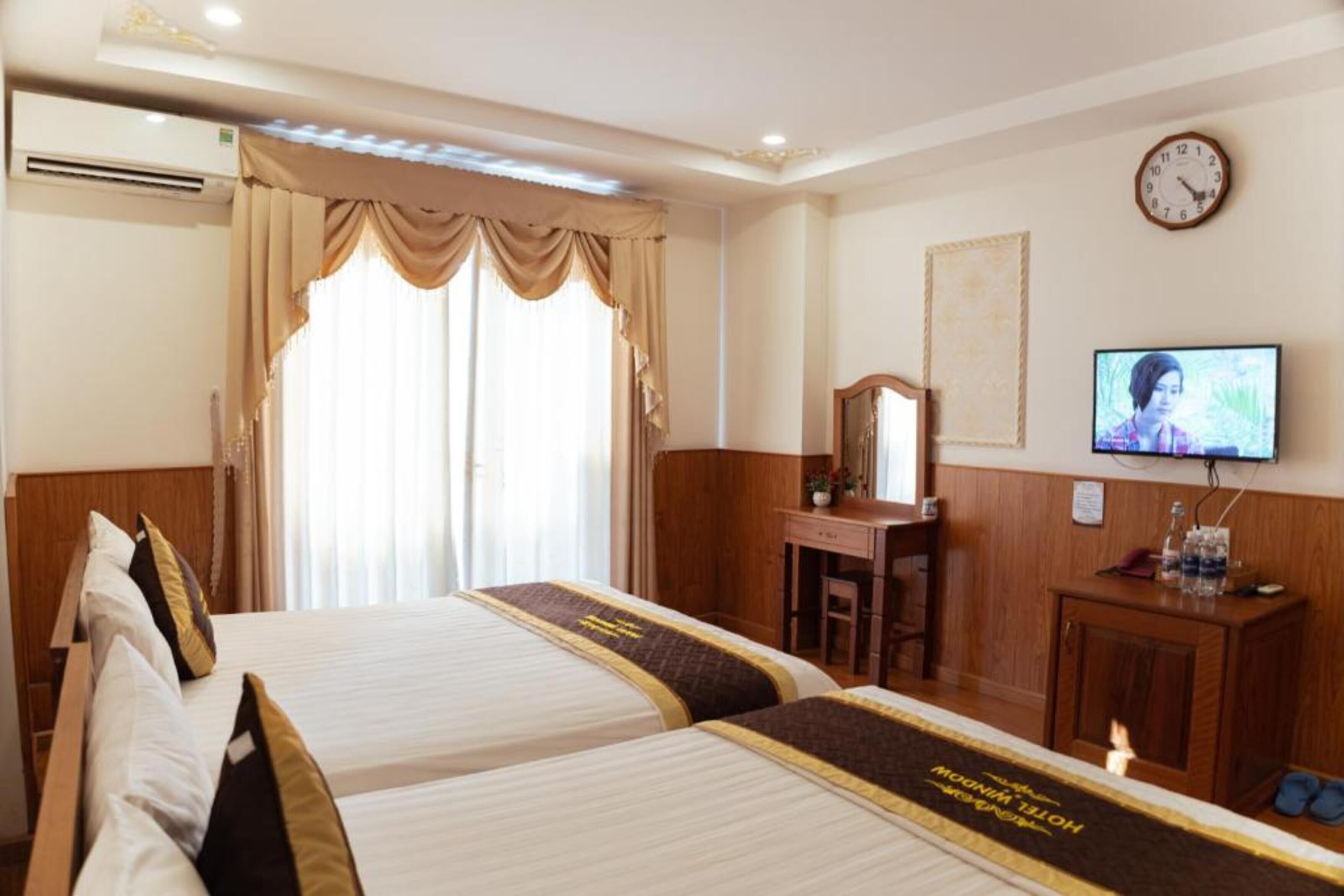 Una habitación de hotel con dos camas, un escritorio, un televisor y un reloj en la pared.