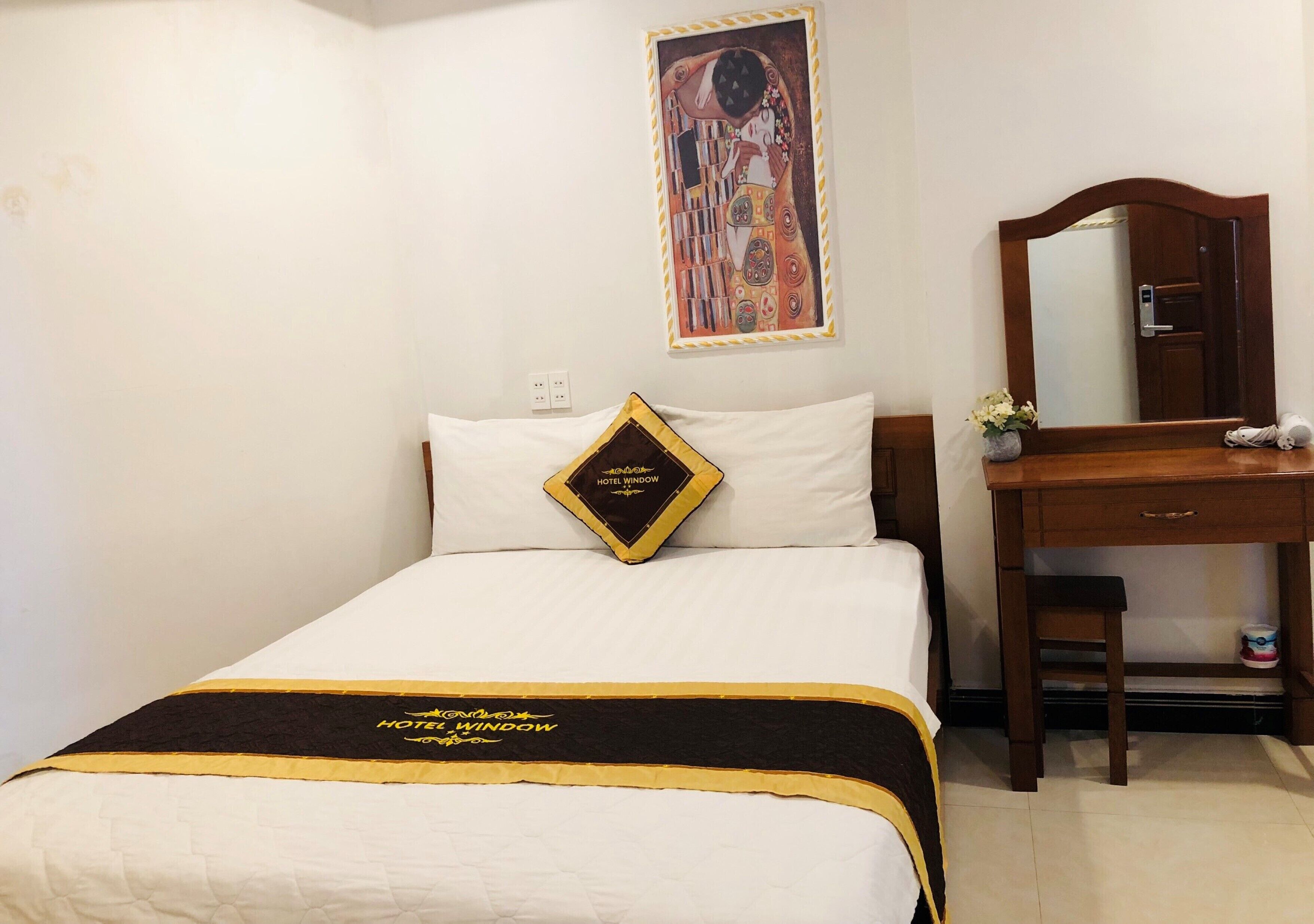 A hotel room with a bed, a nightstand, a mirror, and a painting on the wall.