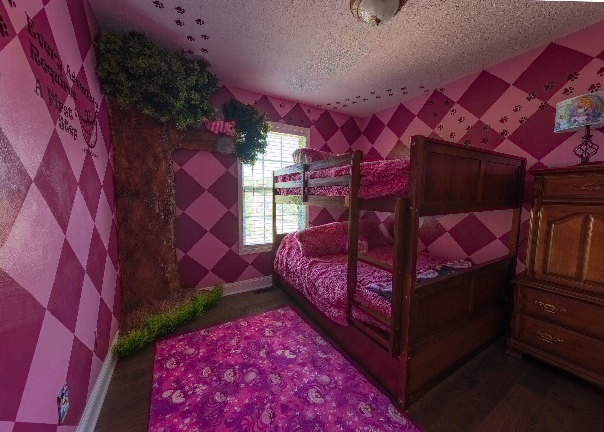 Une chambre avec un lit superposé, une commode et une fenêtre avec des stores.