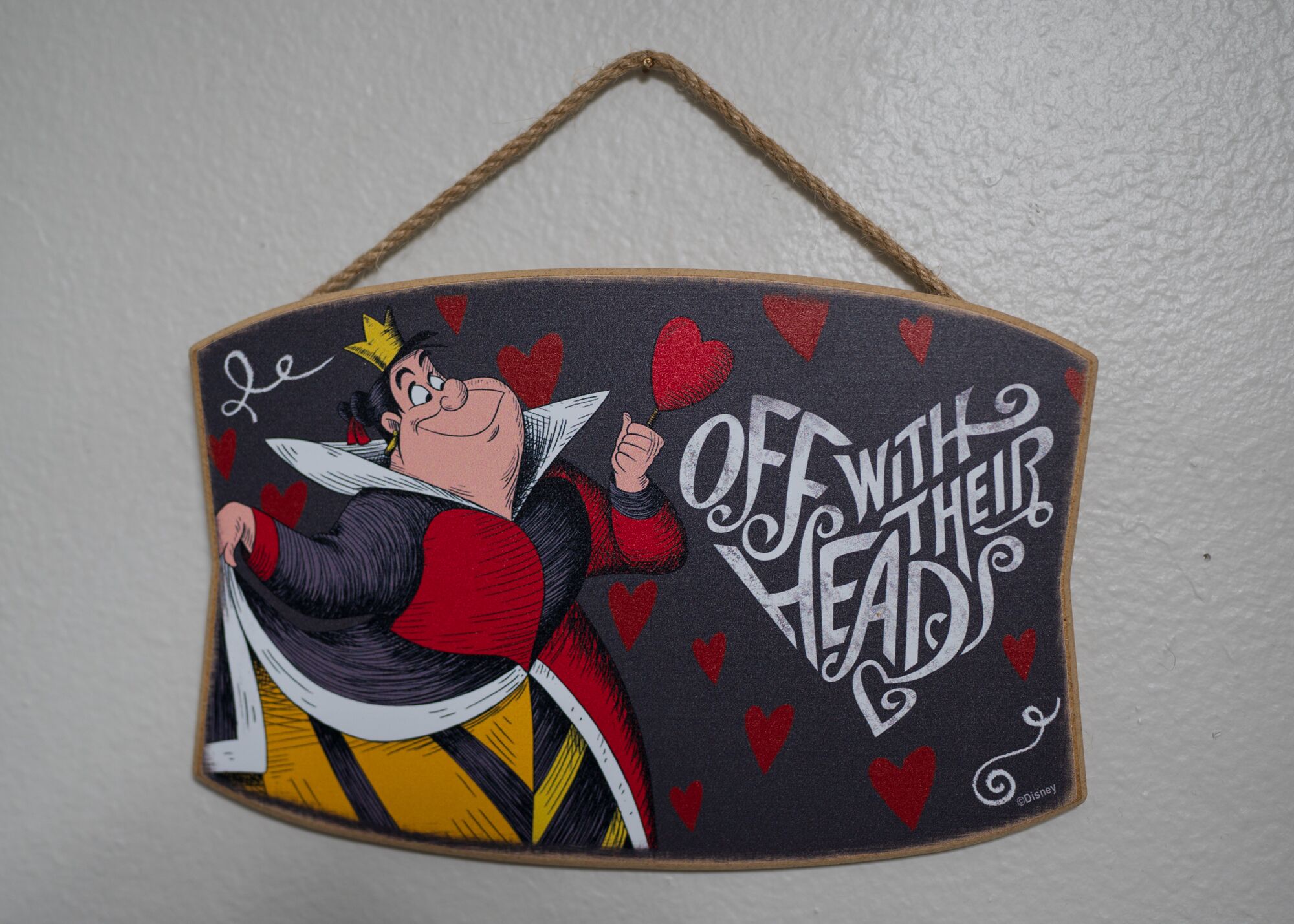 A wall hanging with a character holding a wand and the text "OFF WITH THEIR HEADS".