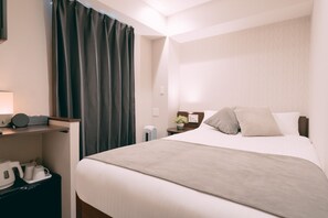 A hotel room with a bed, a bedside table with a lamp, a small table with a plant, and a coffee maker on the floor. - R Hotel Honmachi (Osaka)