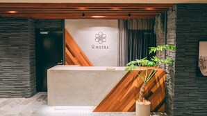 A hotel reception desk with a modern design, featuring a wooden accent wall, a stone wall, and a reception area with a logo. - R Hotel Honmachi (Osaka)