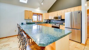 Una cocina moderna con una isla grande, taburetes de madera y un refrigerador de acero inoxidable.