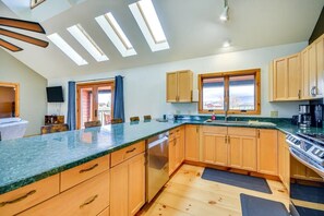 A modern kitchen with wooden cabinets, a granite countertop, and skylights. - Cody retreat with a view and hot tub (Cody)