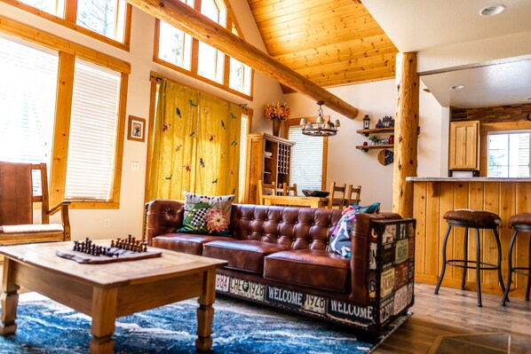 Ein gemütliches Wohnzimmer mit einem braunen Ledersofa, einem Holztisch und einem alten Koffer als Couchtisch.