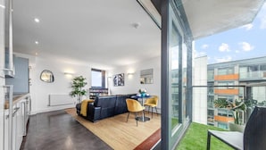 A modern apartment with a living area, dining space, and a large window offering a view of the city. - Lovely & Cosy 2 Beds London Skyline View (London)