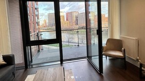 Une chambre moderne dotée d’une grande porte-fenêtre coulissante donnant sur un balcon, d’une chaise et d’un radiateur.