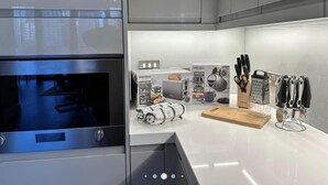 Une cuisine moderne équipée d’un four encastré, d’une machine à café et d’un bloc à couteaux.