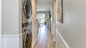 A hallway with a built-in washer and dryer, a dining area with a table and chairs, and a view of the outside through a glass door. - Step out to Pool and Beach, Huge Patio, 2nd Pool Heated, Minutes to Downtown, $300 in Free Tickets! (St. Augustine Beach)