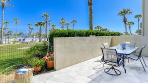 A patio with a table and chairs, a view of the pool, and palm trees. - Step out to Pool and Beach, Huge Patio, 2nd Pool Heated, Minutes to Downtown, $300 in Free Tickets! (St. Augustine Beach)