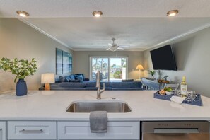 A modern kitchen with a central island, a built-in dishwasher, and a large window offering a view of the outdoors.