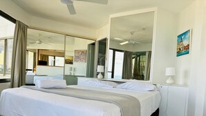 A hotel room with two beds, a large mirror, ceiling fans, and a view of the outdoors. - One Bed Room Ocean View With Surfers Holiday Accommodation - Aloha Apartments (Surfers Paradise)