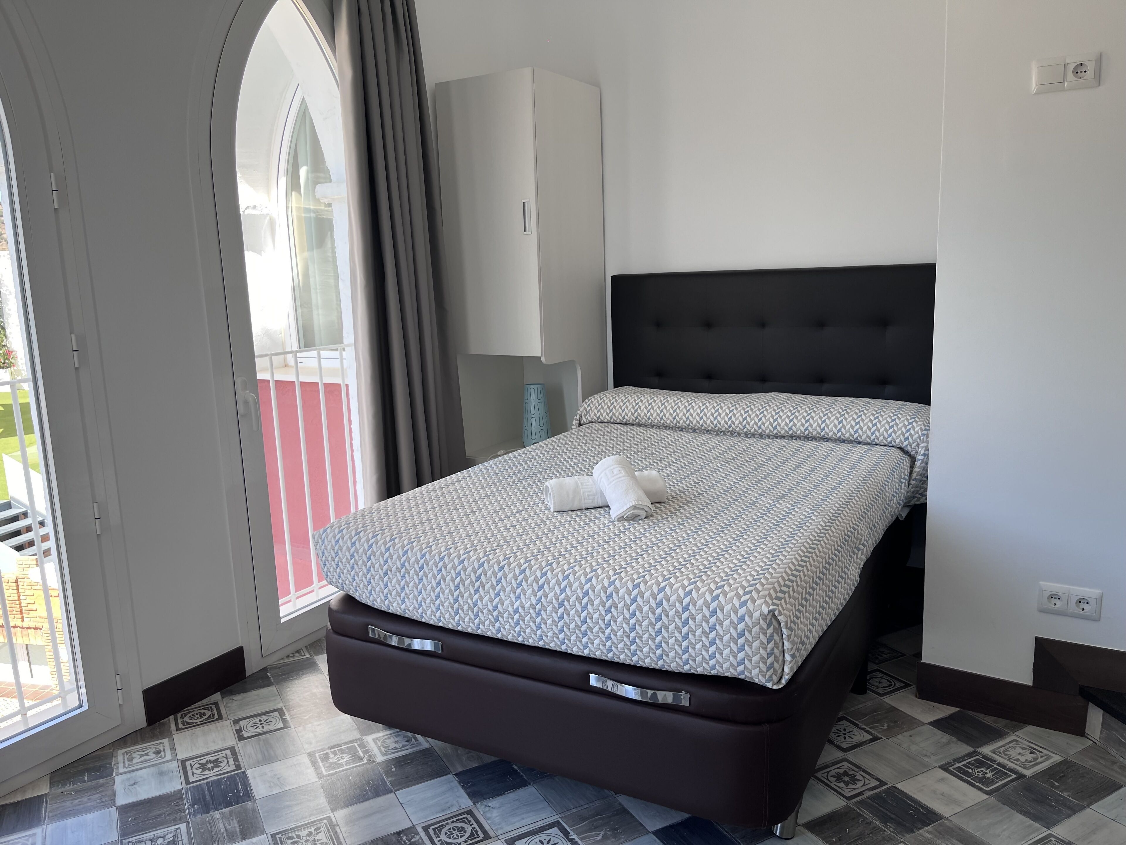 A bedroom with a bed, a wardrobe, and a window with curtains.