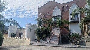 Un bâtiment à la façade évoquant un château, avec un escalier et une enseigne indiquant « Bentos de Bentomiz, appart’hôtel ».