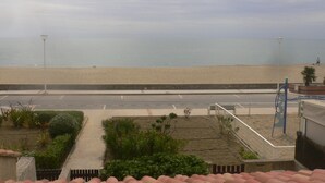 Une route côtière bordée d’une plage de sable et offrant une vue dégagée sur la mer.