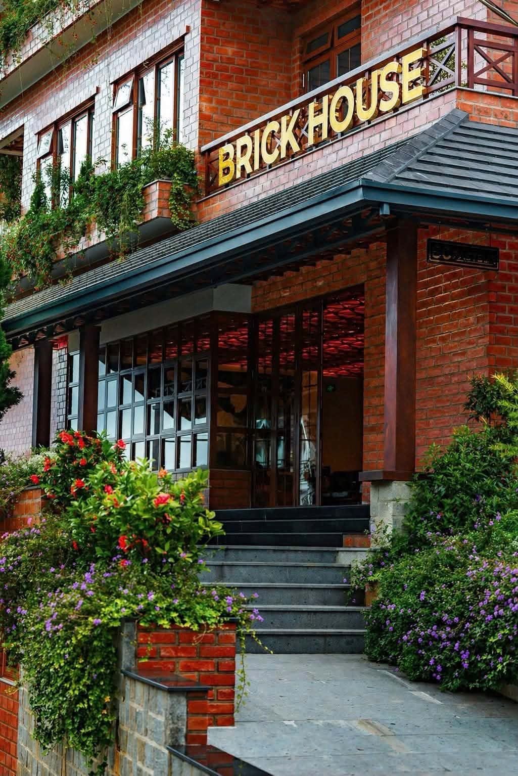 Un edificio de ladrillo con un letrero que dice 'BRICK HOUSE' y un porche cubierto con escalones que conducen a la entrada.