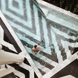 A man in a swimming pool with a geometric tile design. - Hotel Verdigris (Phuket)